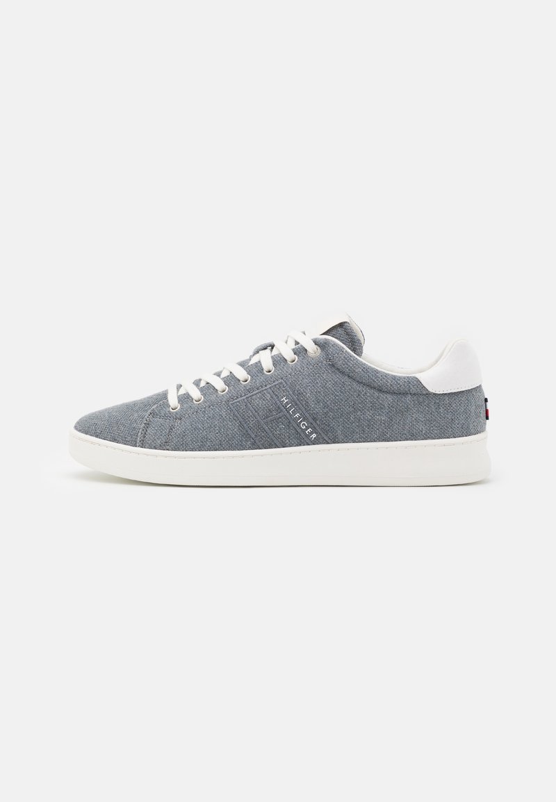 Sneaker in tessuto grigio a bassa punta con lacci e suola bianchi, linguetta sul tallone bianca e marchio "Hilfiger" sul lato.