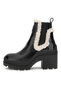 Botas Chelsea de charol negro con ribete de pelo sintético, suela de goma negra gruesa, tacón estriado y tirador en la parte trasera para facilitar su uso.