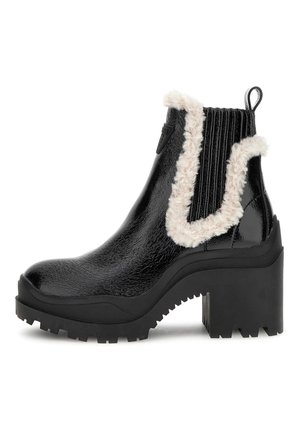 Botas Chelsea de charol negro con ribete de pelo sintético, suela de goma negra gruesa, tacón estriado y tirador en la parte trasera para facilitar su uso.