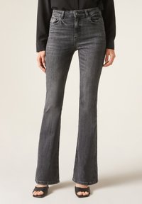 Jean flair noir avec taille haute, en denim. Comprend des poches avant et une texture légèrement décolorée, avec une taille ajustée et des jambes plus larges.