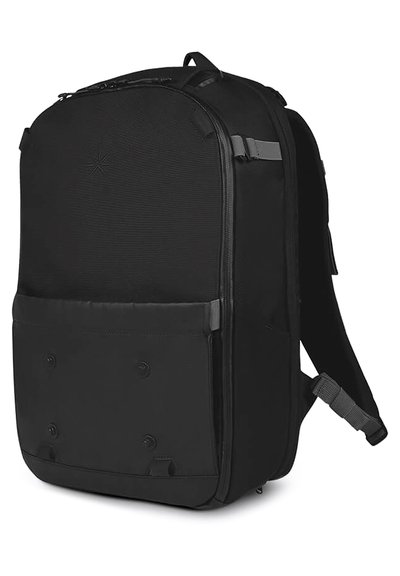 Zaino nero realizzato in tessuto resistente, dotato di chiusura con zip, tasca frontale con bottoni a pressione e spallacci regolabili e imbottiti.