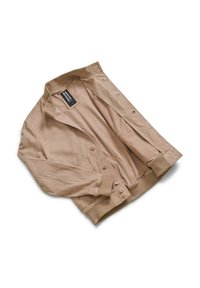 Giacca beige realizzata in tessuto morbido, con colletto, chiusura con bottoni e polsini a coste. Include tasche laterali ed è sfoderata.