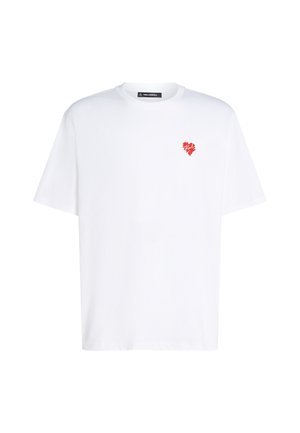 Hvid bomulds T-shirt med et lille rødt hjerte-design på venstre bryst. Klassisk rund hals og korte ærmer. Enkel og afslappet pasform.