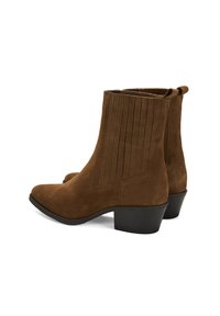 Bottes chelsea en daim marron à bout pointu, avec des panneaux latéraux côtelés et un petit talon empilé noir. Comprend des anses pour un enfilage facile.