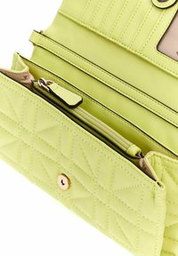 Pochette en cuir vert citron matelassé avec une fermeture à pression dorée, dotée d'un intérieur texturé et de plusieurs compartiments de rangement.