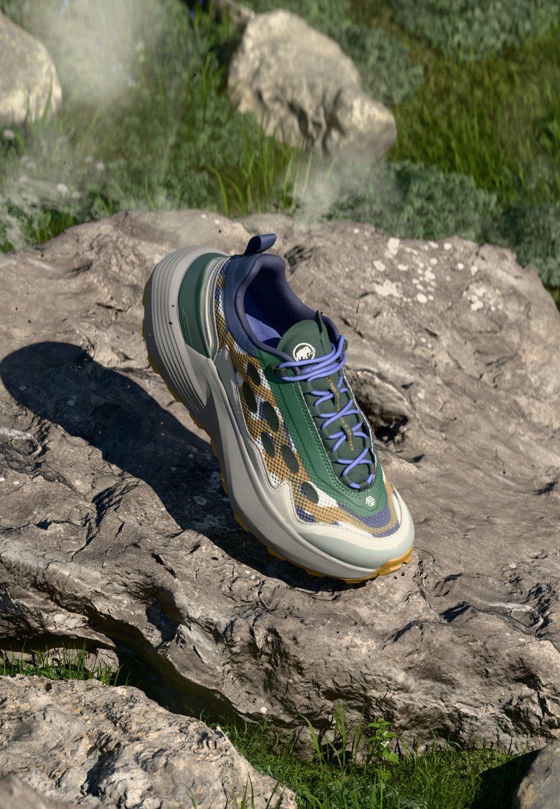 Spordijalatsid, millel on rohelisest ja beežist kangast mustriga pealmine osa, paks hall vahekiht ja lillakad aktsendid, paigutatud kivisele pinnale.