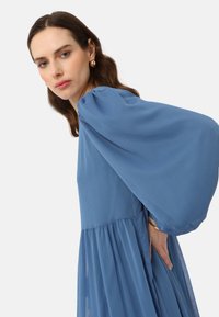 Long-sleeve blue dress with a textured, flowing fabric. Features voluminous puff sleeves and a fitted bodice with a flared skirt.