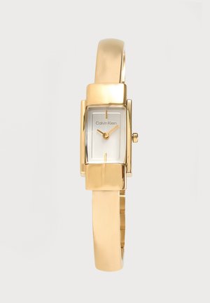 Montre-bracelet rectangulaire Calvin Klein ton or avec cadran blanc minimaliste et index et aiguilles dorés sur un bracelet métallique fin.