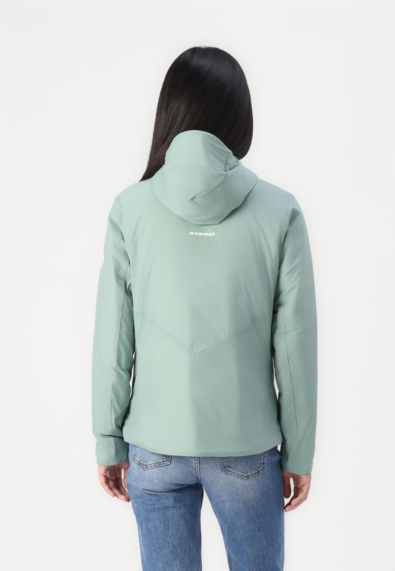 Zielona kurtka z kapturem o gładkiej fakturze i materiałach wodoodpornych. Posiada trójkątny wzór szwów na plecach oraz logo na górnej części pleców.