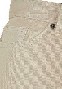 Tela de mezclilla beige con una superficie ligeramente texturizada, que presenta un diseño de yugo, costuras decorativas y un detalle de botón met�álico.