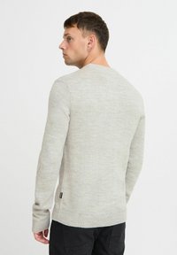Maglione lavorato a maglia grigio chiaro con maniche lunghe, polsini e orlo a coste, caratterizzato da una sottile texture e da un piccolo etichetta con logo in basso a sinistra.