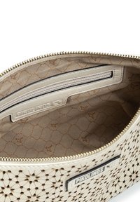 Bolso de crema texturizado con un diseño perforado, cierre dorado y un interior de marca que presenta un patrón geométrico en marrón claro.