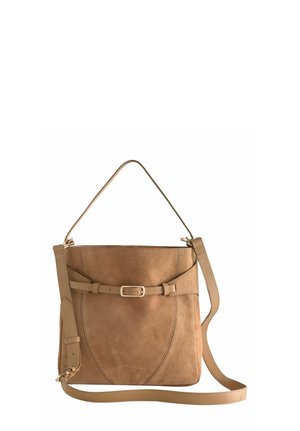 Tan leather crossbody bag with adjustable shoulder strap and decorative belt detail on the front against white background.
