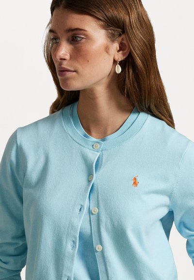 Cardigan azzurro chiaro realizzato in un tessuto morbido, con colletto tondo, chiusura con bottoni e un logo ricamato arancione sul lato sinistro del petto.