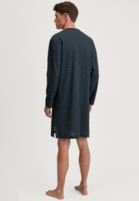 Nachthemd in Navy mit langen Ärmeln, einem weißen Rautenmuster, aus weichem Stoff und seitlichen Schlitzen für mehr Bewegungsfreiheit.