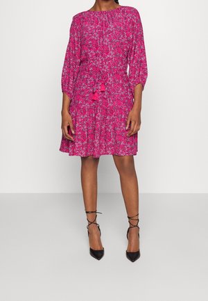 Růžové květinové šaty s kulatým výstřihem, tříčtvrtečními rukávy a řaseným pasem. Obsahují střapcové ozdoby a rozšířenou sukni.