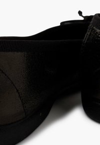 Scarpe slip-on nere con finitura lucida, dotate di un elastico nero all'apertura e design minimalista. Tessuto morbido e liscio.