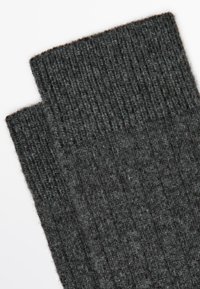 Chaussettes rayées gris foncé en tissu texturé, avec un bord supérieur replié et un motif uniforme sur l'ensemble du matériau.