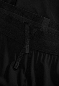 Zwarte sportshorts met een brede elastische tailleband en een binnenste trekkoord, een gladde textuur en een minimalistisch design.