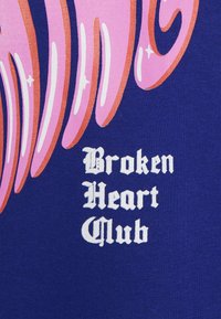 Tmavě modrá látka má živý růžový abstraktní motiv s zakřivenými tvary. Text zní „Broken Heart Club“ bílým, stylizovaným písmem.