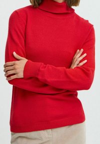 Maglione rosso a collo alto lavorato a maglia con maniche lunghe, polsini e orlo a coste. Tessuto liscio con un design aderente.