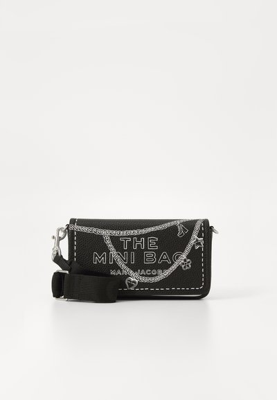 Bolso mini sintético negro con gráfico de cadena blanca, logotipo "THE MINI BAG", cierre de cremallera, correa desmontable y acentos decorativos de hardware.