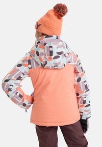 Giacca invernale colorata con un corpo rosa e cappuccio decorato con forme geometriche in colori pastello. Include un berretto con pompon in cima.