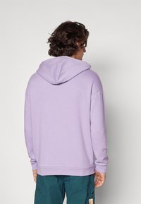 Felpa con cappuccio viola, dal taglio morbido, maniche lunghe, orlo a coste e texture liscia. Un design semplice e funzionale.