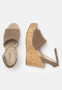 Tanfarbene Wildleder-Wedgesandalen mit einer Korkplattform, offener Zehenpartie und einem Knöchelriemen, der mit kleinen metallischen Nieten verziert ist. Glatter Innenfutter.