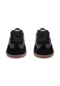 Mustad mustad, millel on nahast ja tekstureeritud nubukist ülemine osa. Ümmargune varvas, lamedad paelad, pruun kummist välistald ja hallid tekstiilid külgedel.