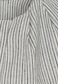 Bomuldsstof med lodrette striber i blå og hvid, med en blød tekstur og en subtil glans, arrangeret i et flydende mønster.