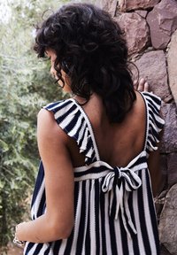 Haut sans manches rayé bleu marine et blanc, avec des bretelles à volants et un nœud dans le dos. Tissu doux avec une coupe ample.