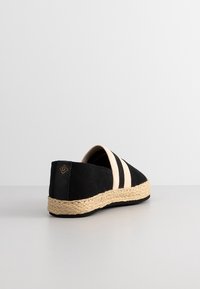 Espadrille en toile noire avec des rayures beiges, bout arrondi et semelle en jute tressé. Présente un petit logo sur la partie du talon.