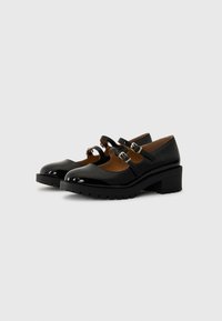 Schwarze Lackleder-Mary-Jane-Schuhe mit zwei geschnallten Riemen, abgerundeter Spitze und einem stabilen Absatz, ausgestattet mit einer strukturierten Gummisohle für guten Halt.