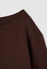 Felpa in cotone marrone con scollatura ampia e vestibilità morbida. Cuciture visibili lungo i bordi, texture liscia e tessuto morbido.