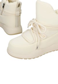 Beżowe sneakersy na platformie o gładkim, błyszczącym wykończeniu, wyposażone w sznurowadła, wyściełany kołnierz i podwójne zamki błyskawiczne dla pewnego dopasowania i stylu.