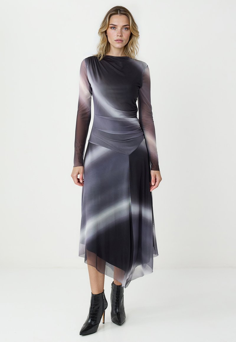 Sukienka z długim rękawem w gradientowych odcieniach szarości, z falbaniastym krojem i asymetrycznym hemem. Gładki materiał o delikatnym połysku. Czarne botki za kostkę.