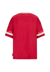 Czerwona bawełniana koszulka z krótkim rękawem, z białymi i czerwonymi paskami na rękawach oraz nadrukowanym napisem "NEW YORK CITY RETOUR" na plecach.