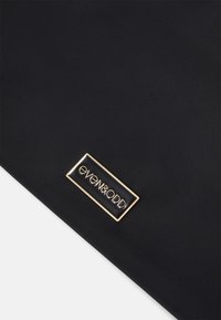 Black fabric with a smooth texture featuring a rectangular, gold-framed logo tag that reads "even&odd." No additional embellishments.