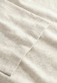 Ύφασμα από βαμβάκι ανοιχτού γκρι με λεία υφή, που διαθέτει διπλωμένη άκρη με απλό σχέδιο ραφής. Ορατό διακριτικό σχέδιο heather.