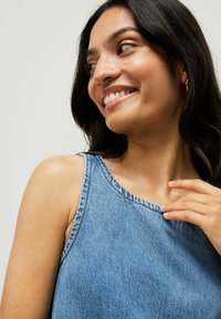 Denim-Top mit Rundhalsausschnitt und breiten Trägern, in einem hellblauen Farbton und mit einem dezenten strukturierten Stoff.