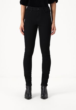 Černé skinny džíny s hladkým povrchem, pěti kapsami a zapínáním na knoflík. Kombinované s černými kotníkovými botami.