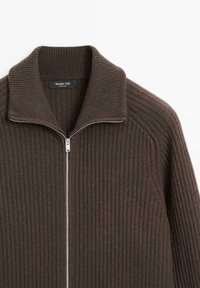 Brązowy sweter z prążkowanym wzorem, zapinany na zamek, z wysokim kołnierzem i srebrnym zamkiem. Posiada teksturowany materiał oraz metkę wewnątrz dekoltu.