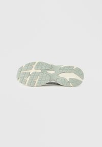 Σόλα παπουτσιού από γκρι και κρεμ καουτσούκ, με υφή και προεξοχές βαθείς για καλύτερη πρόσφυση και στήριξη. Κυκλικό άνοιγμα στο κέντρο.