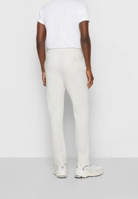 Lichtgrijze, taps toelopende broek met een elastische tailleband en zijzakken, gecombineerd met een wit t-shirt en lichtgekleurde sneakers.