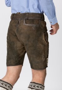 Shorts en cuir marron avec une finition texturée, dotés de coutures décoratives et d'une poche latérale avec des accents détaillés. Taille ajustable.