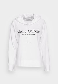 Sudadera blanca de tejido suave con un bolsillo canguro. Texto negro "Marc O'Polo EST. IN STOCKHOLM" impreso en la parte delantera.