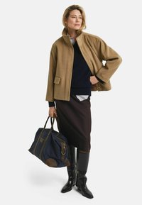 Brown wool blend coat with high collar, navy knit top, dark pencil skirt, and black crocodile-embossed knee-high boots. Large navy bag with brown accents.