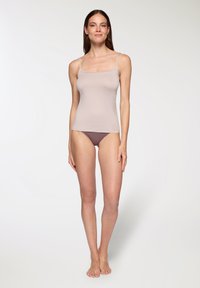 Top in beige chiaro con spalline sottili, realizzato in un tessuto liscio, abbinato a mutandine marroni scure, che mettono in mostra una silhouette aderente.