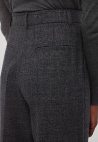 Graue strukturierte Hose mit einem dezenten Karomuster, flachem Frontschnitt, seitlichen Taschen und einer schmalen Passform.